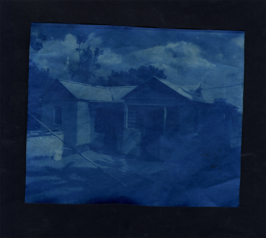 blue cyantype image of a small house in