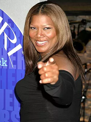 woman with caramel-colored hair wearing black pointing toward viewer